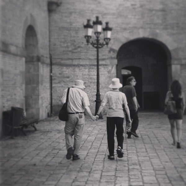 Elihu and Ruth Katz walking in Barcelona, holding hands, viewed from the back