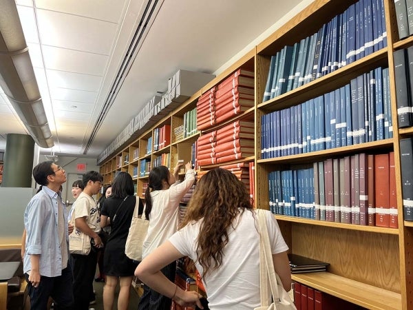 Se-Hoon Jeong with students all looking at a wall of books in the Annenberg Library